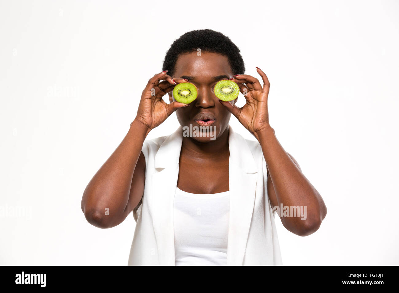 Lustige amüsant afroamerikanische junge Frau mit Kiwi Hälften vor ihren Augen auf weißem Hintergrund Stockfoto