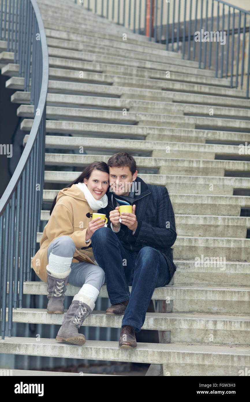 Glücklich lächelnd paar Tee trinken auf einer Treppe Stockfoto