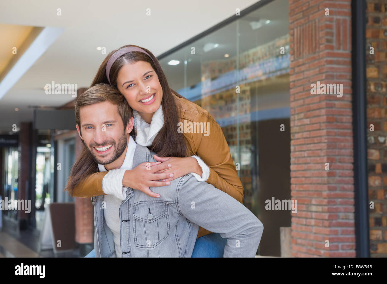 Junger Mann geben einer jungen Frau eine Schweinchen Fahrt Stockfoto
