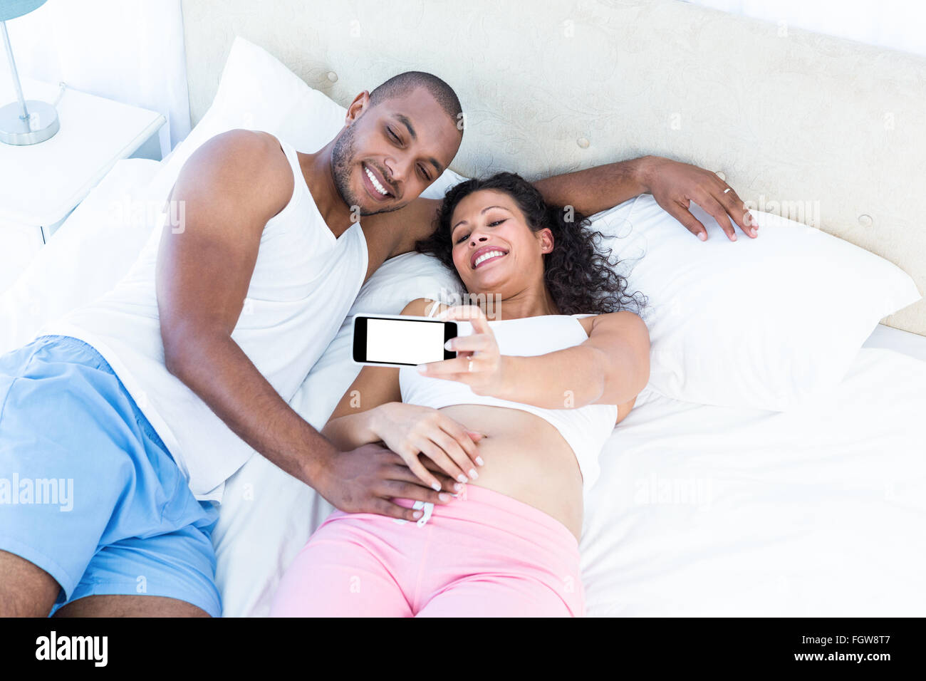 Glückliches Paar klicken Selfie auf Bett liegend Stockfoto