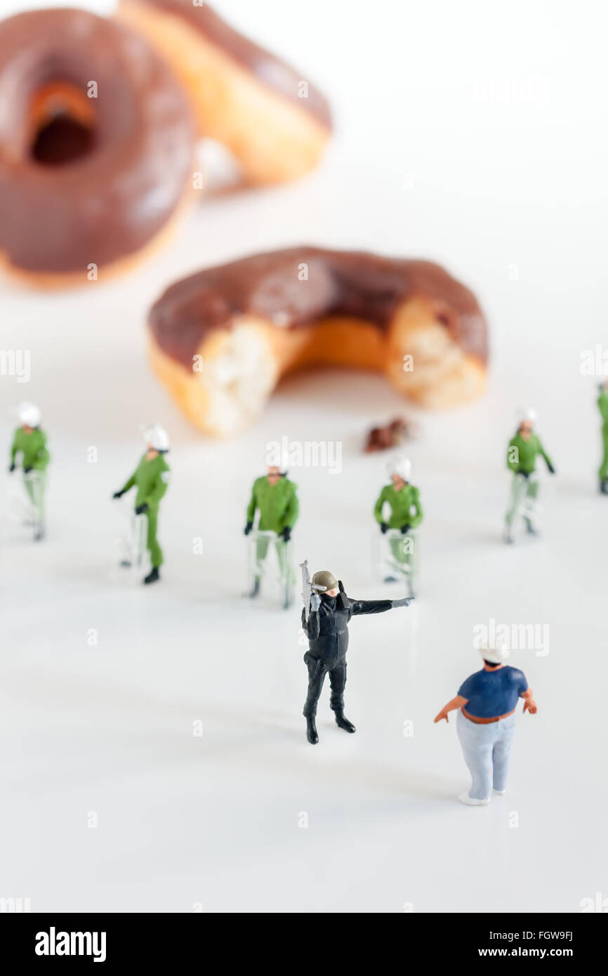 Polizei in Kampfmontur verhindert, dass einen übergewichtigen Mann erreicht Donuts eine Public Health-Konzept Stockfoto