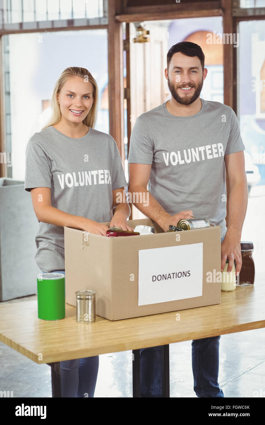 Glücklicher Mann und Frau trennen Spende stopft im Büro Stockfoto