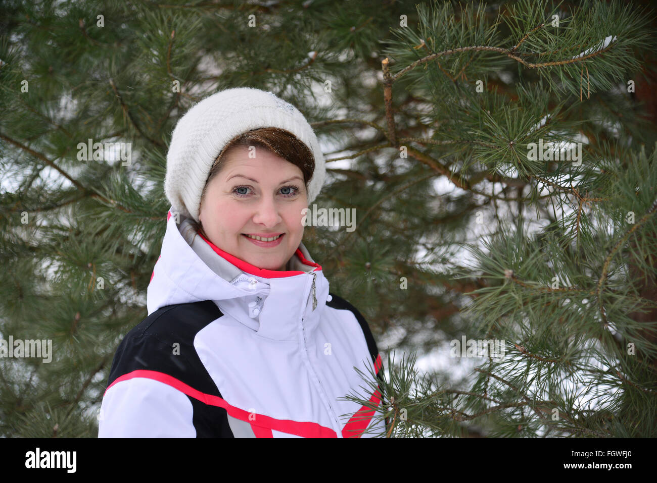 Frau im Sportjacke und Hut im Winter Kiefernwald Stockfoto