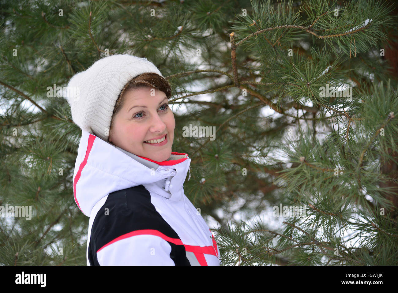Frau im Sportjacke und Hut im Winter Kiefernwald Stockfoto