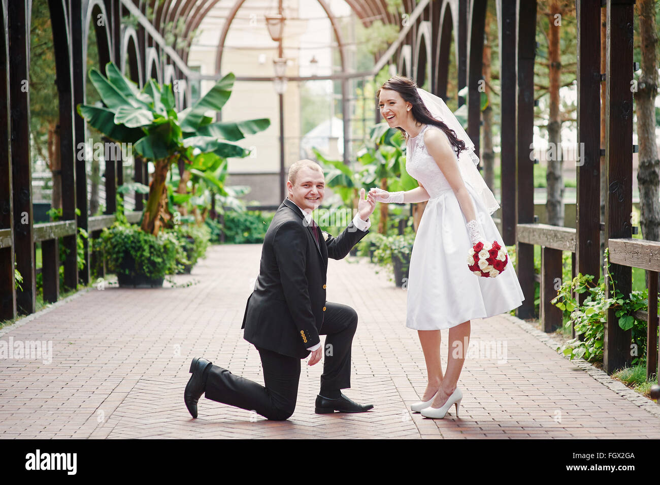 Bräutigam kniet auf einem Knie vor eine glückliche Braut Stockfoto