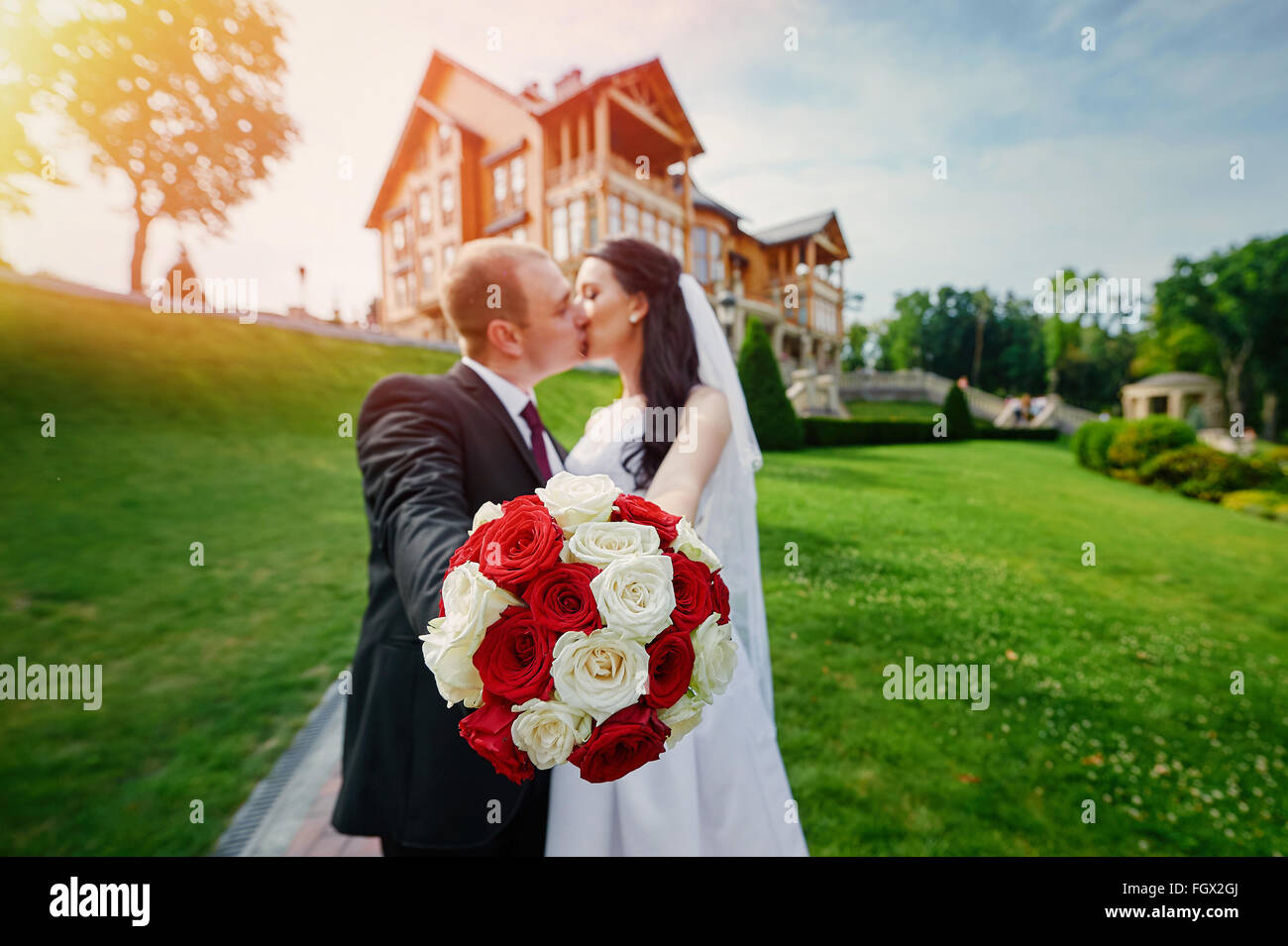 Europäischen Braut und Bräutigam küssen im Park in der Nähe von Haus Stockfoto