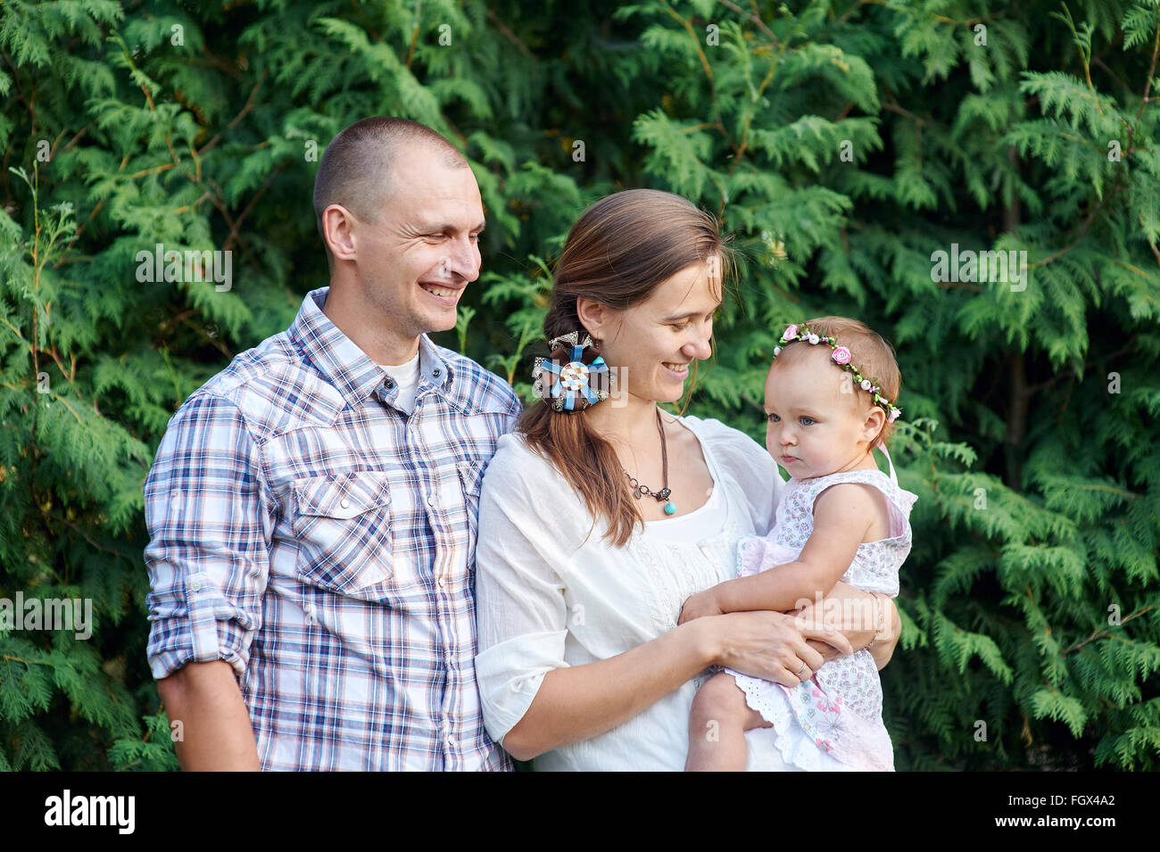 glückliche Familie mit einer kleinen Tochter auf einem Hintergrund aus grünen Blättern Stockfoto