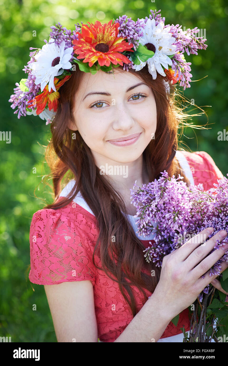 Junge Frau mit Kranz und mit lila Blüten im Frühling Stockfoto