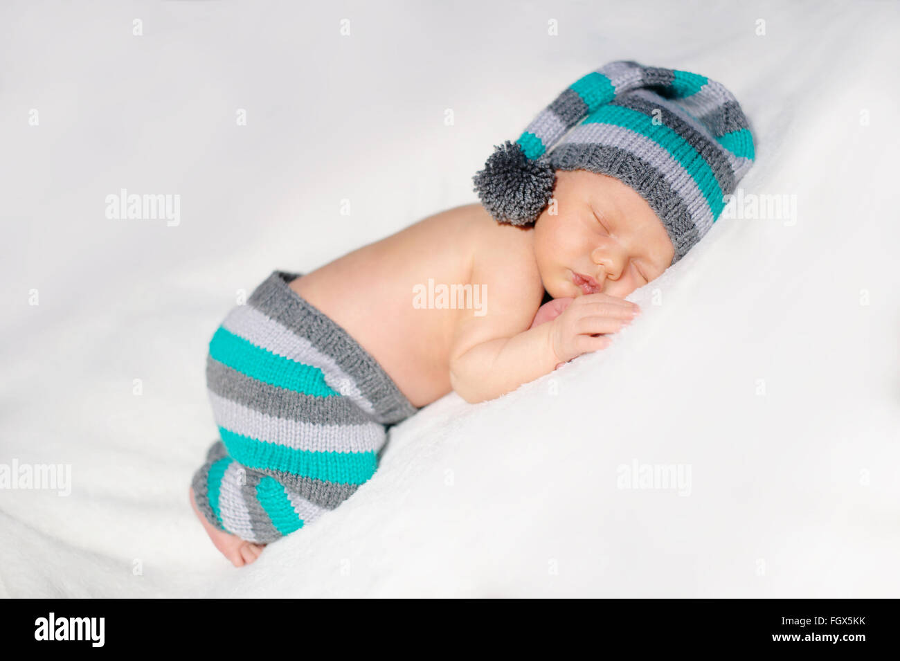 neugeborenes Baby schläft in einem Strick Anzug auf weißem Hintergrund Stockfoto