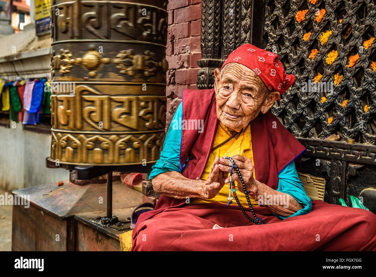 Sehr alte tibetische buddhistische Nonne sitzt und bittet vor einem Heiligtum in Kathmandu Stockfoto