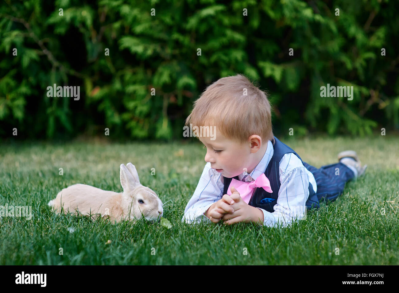 kleiner Junge mit einem Hasen auf dem Rasen liegend Stockfoto