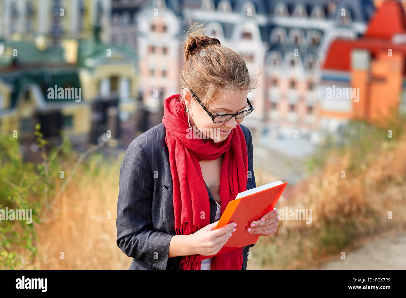 Frau in Gläsern mit dem roten Buch über Stadt Hintergrund Stockfoto