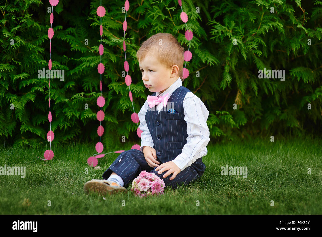 glücklich kleiner Junge sitzt im Sommerpark auf dem Rasen Stockfoto