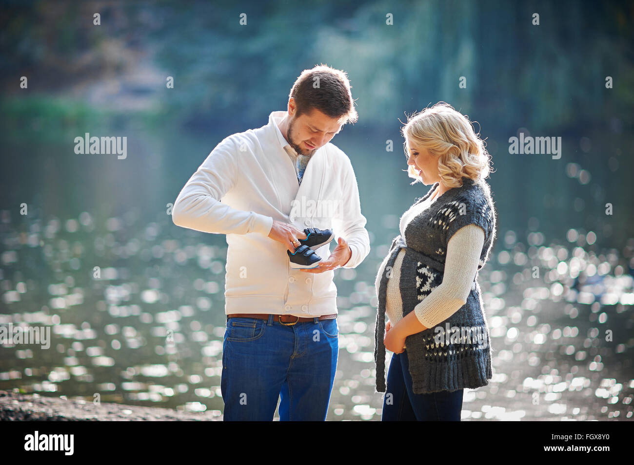 Glückliche schwangere Frauen und ihr Mann während der Wanderung mit einem Mann in der Nähe des Sees Stockfoto