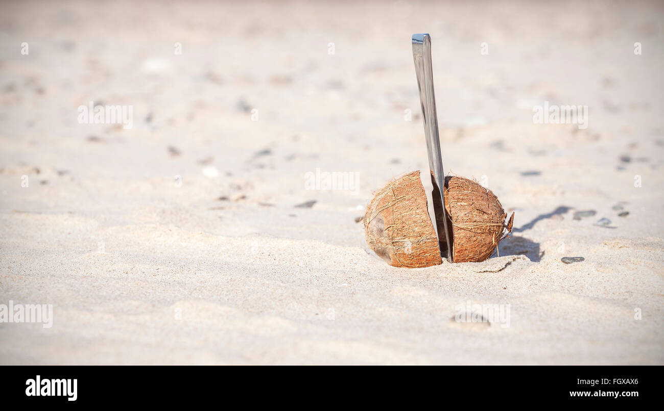 Kokosnuss halbiert mit Messer an einem Strand. Stockfoto