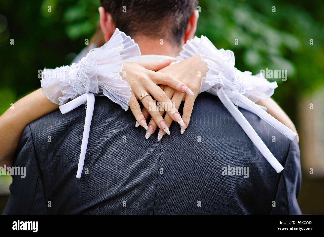 Braut umarmt des Bräutigams Hals Stockfoto