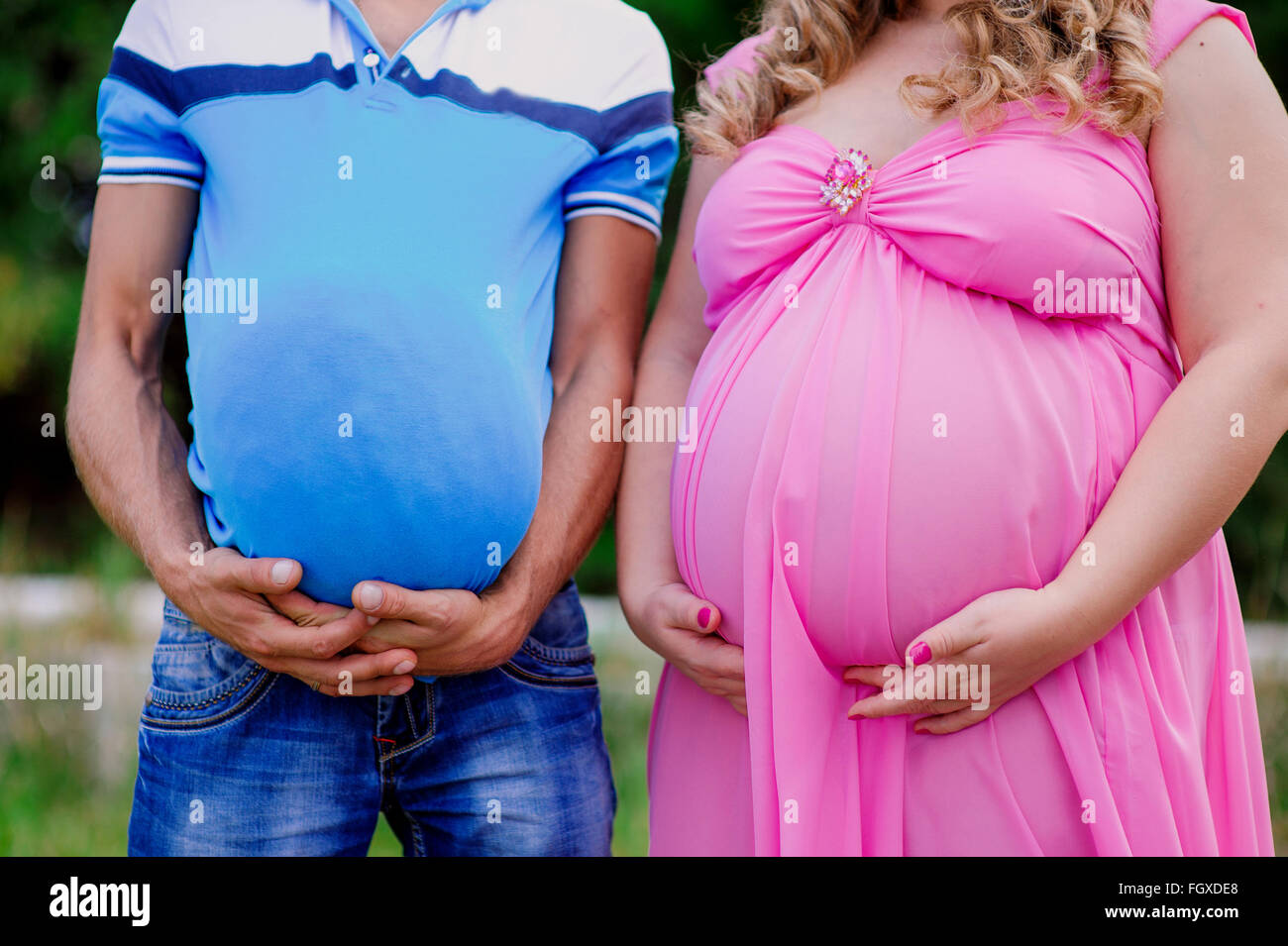 Mann und schwangere Frau halten beide mit ihren großen Mägen Stockfoto