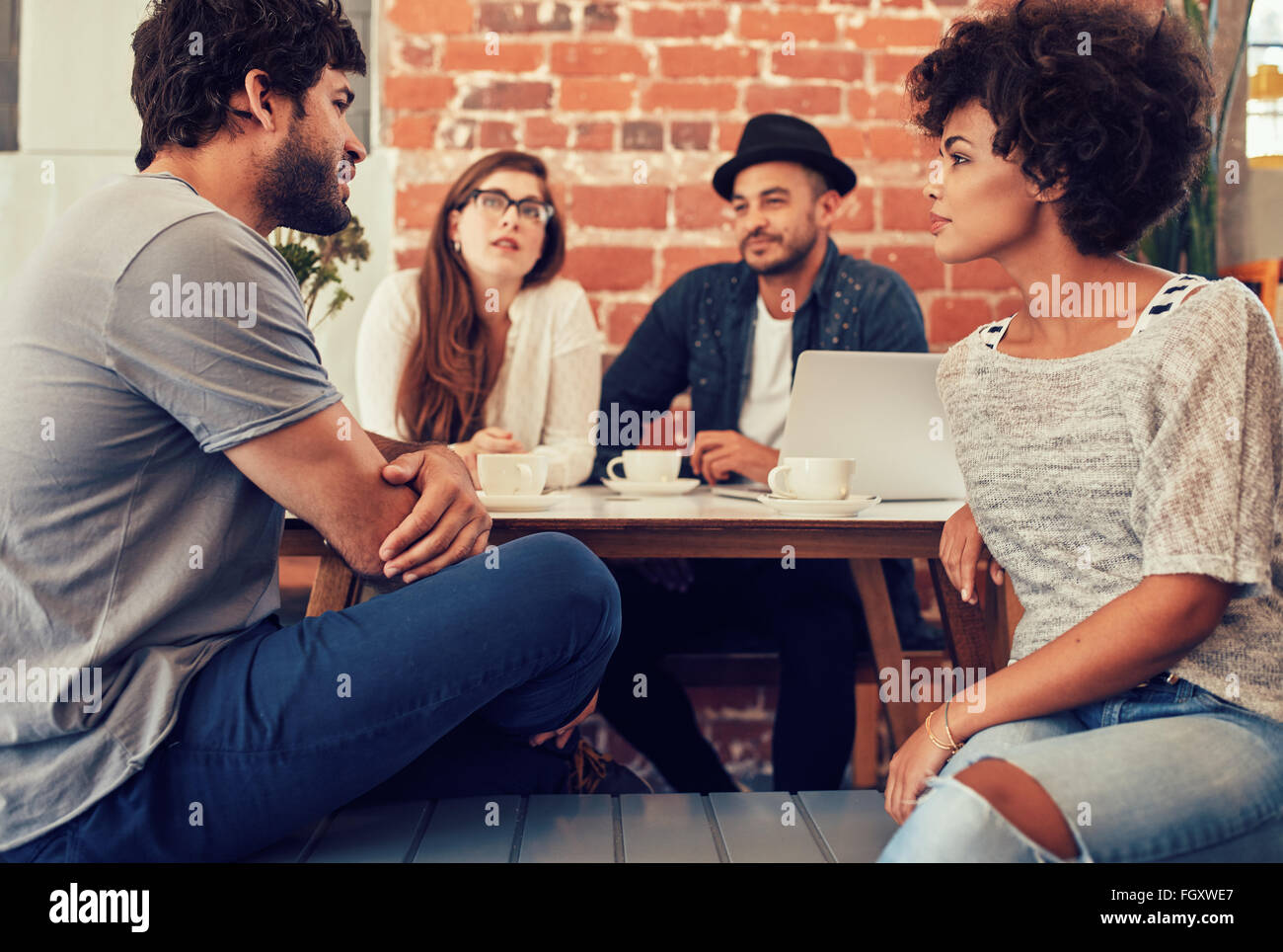 Gruppe junger Freunde sitzen und reden in einem Café. Junge Männer und Frauen in einem Café zu treffen und zu diskutieren. Stockfoto