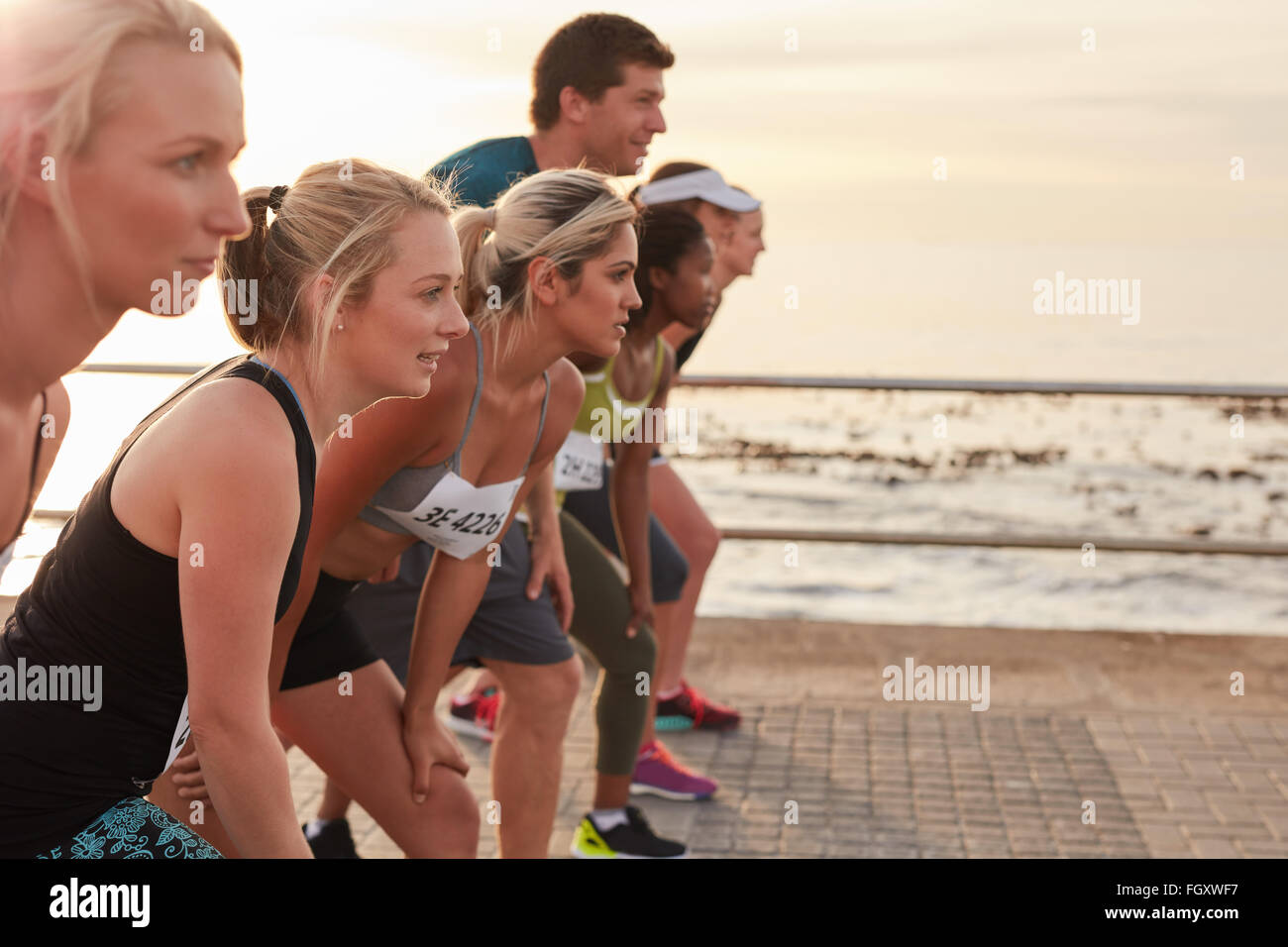 Läufer auf der Linie zu Beginn eines Rennens stehen. Gruppe von jungen Menschen eine Ausbildung für Marathon-Rennen auf der Straße am Meer. Stockfoto