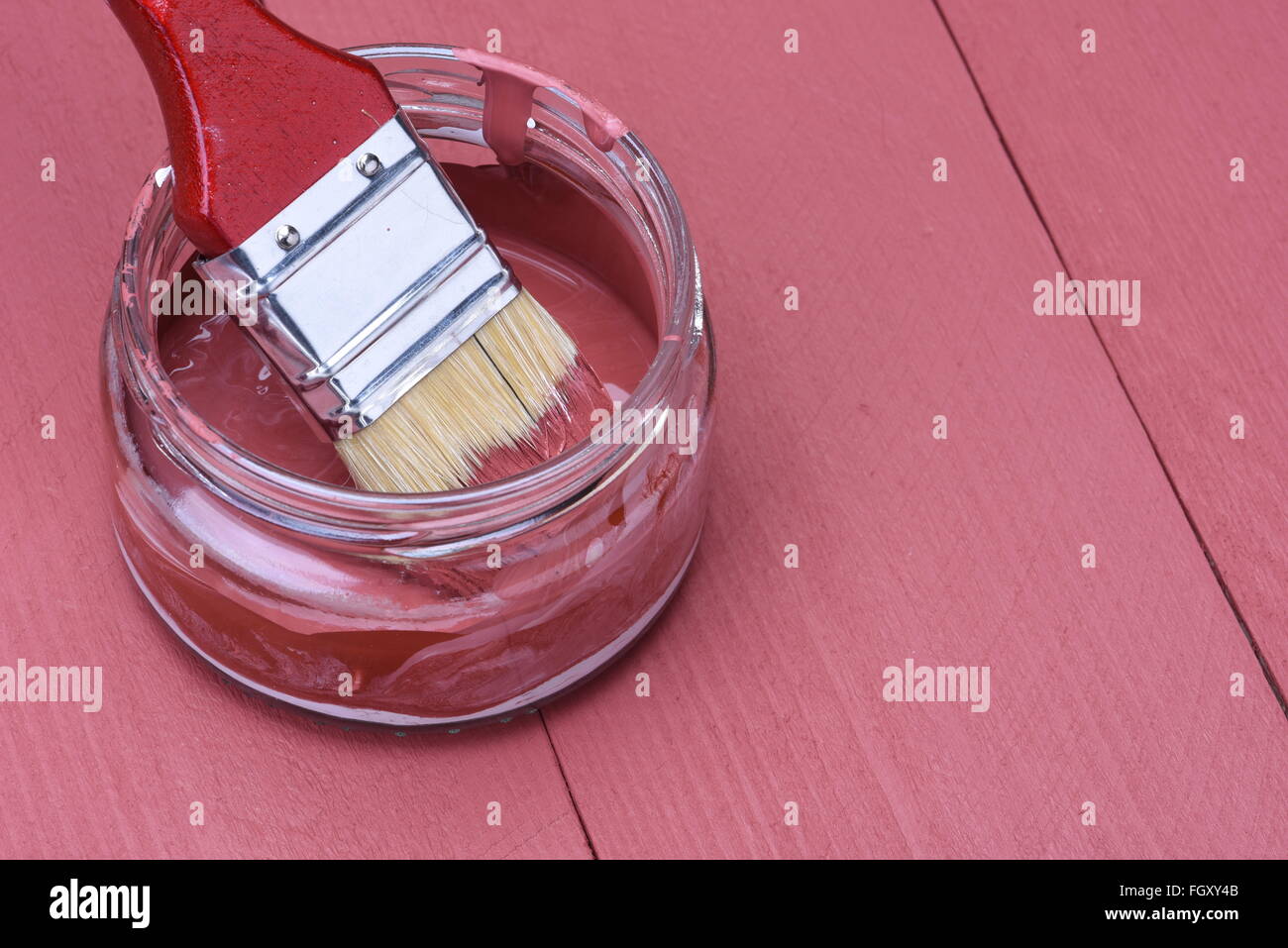 Rosa Farbe in ein Glas mit Pinsel auf Holzbrett Hintergrund Stockfoto