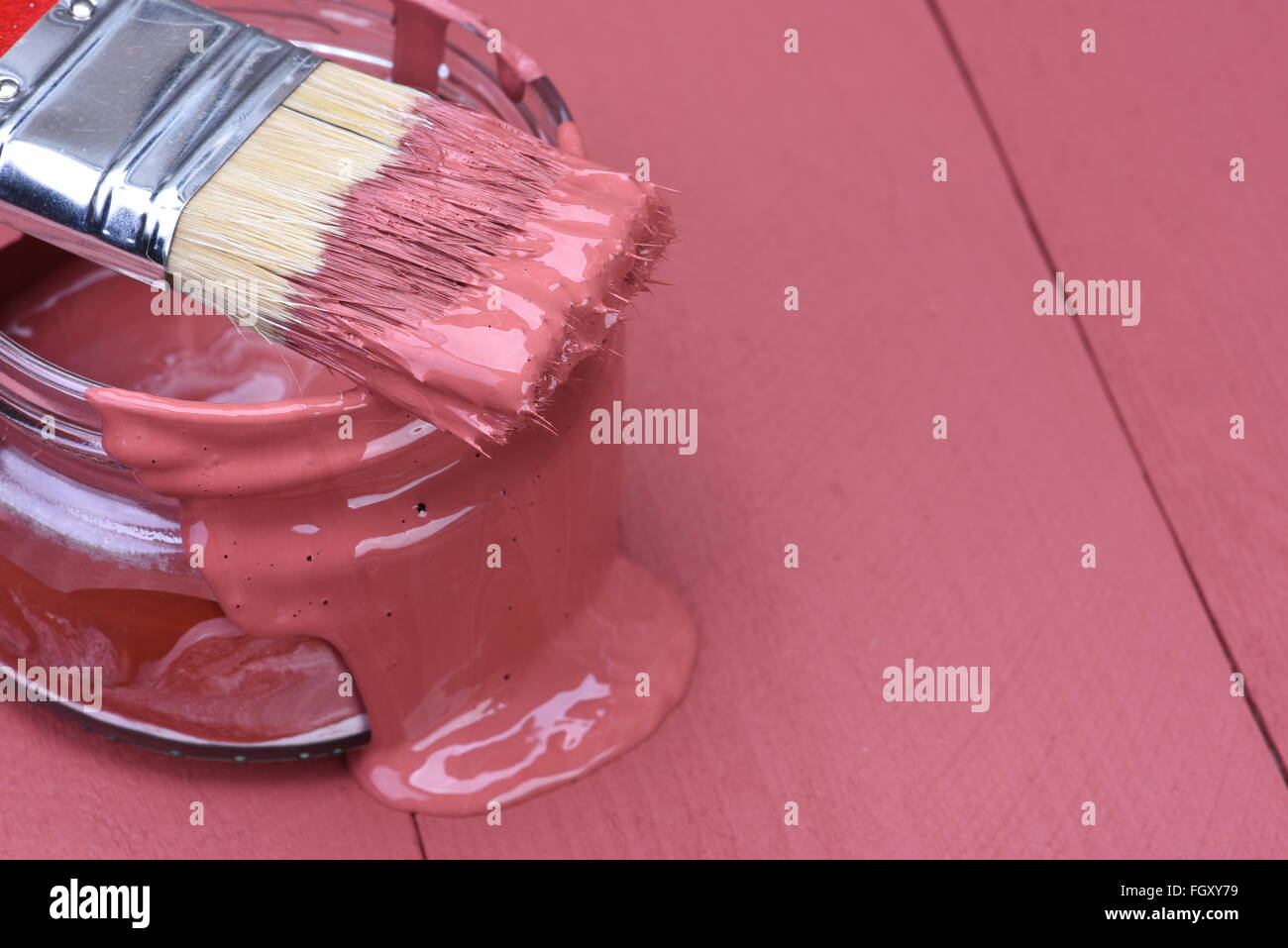 Rosa Farbe in ein Glas mit Pinsel auf Holzbrett Hintergrund Stockfoto