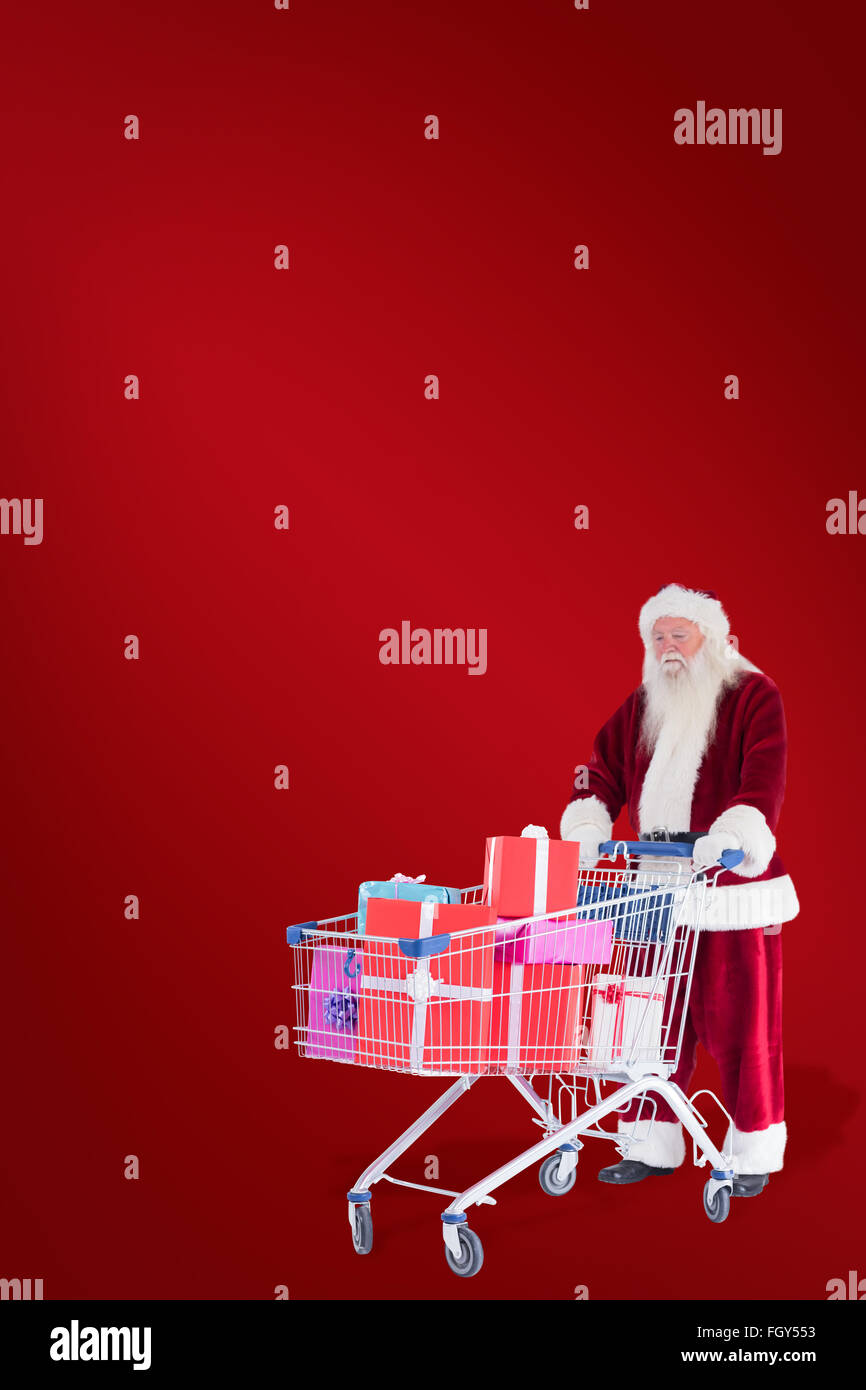 Zusammengesetztes Bild von Santa schiebt einen Einkaufswagen mit Geschenken Stockfoto