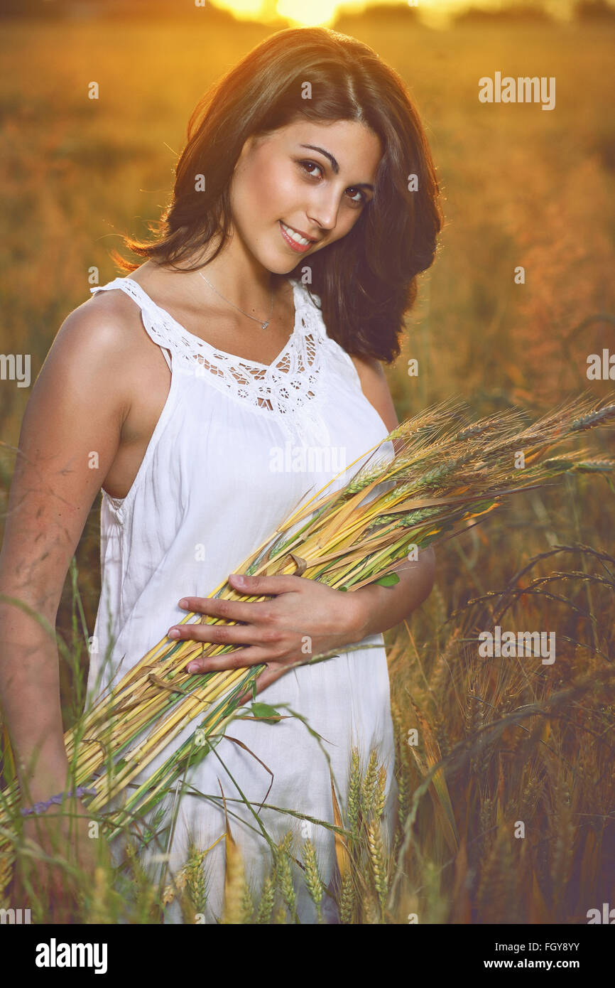 Schöne Frau in einem goldenen Getreide-Feld umgeben von Sommer Abendlicht Stockfoto