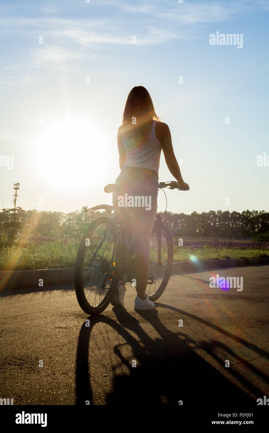 Zurück Blick Silhouette sportlich schöne junge Frau auf Mountainbike tragen legere Kleidung am Sommertag, Sonne Stockfoto