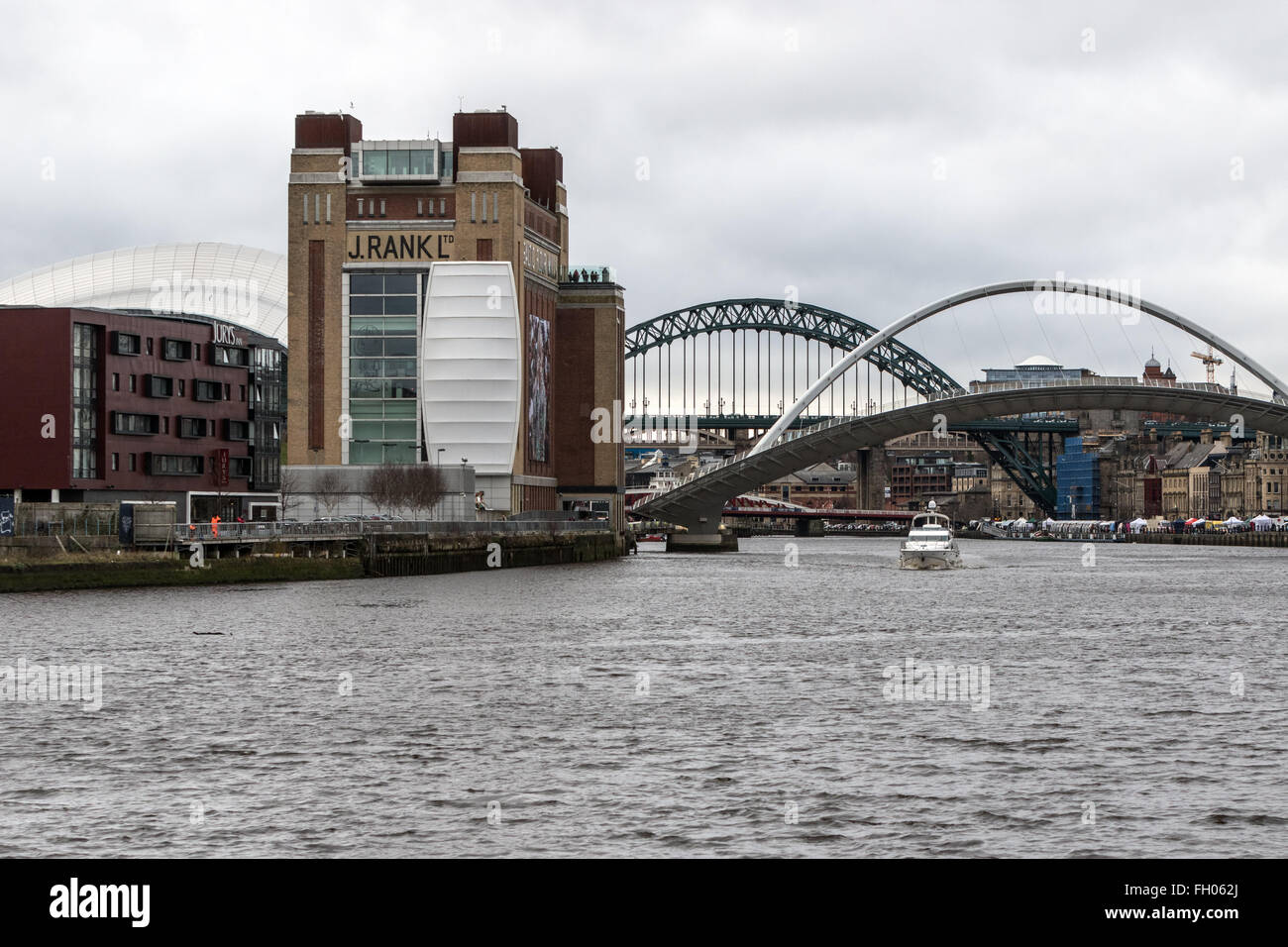 Ein Sportboot segelt hinunter den Tyne wie die Gateshead Millennium Bridge mit dem Tyne Bridge im Hintergrund ausgelöst wird Stockfoto