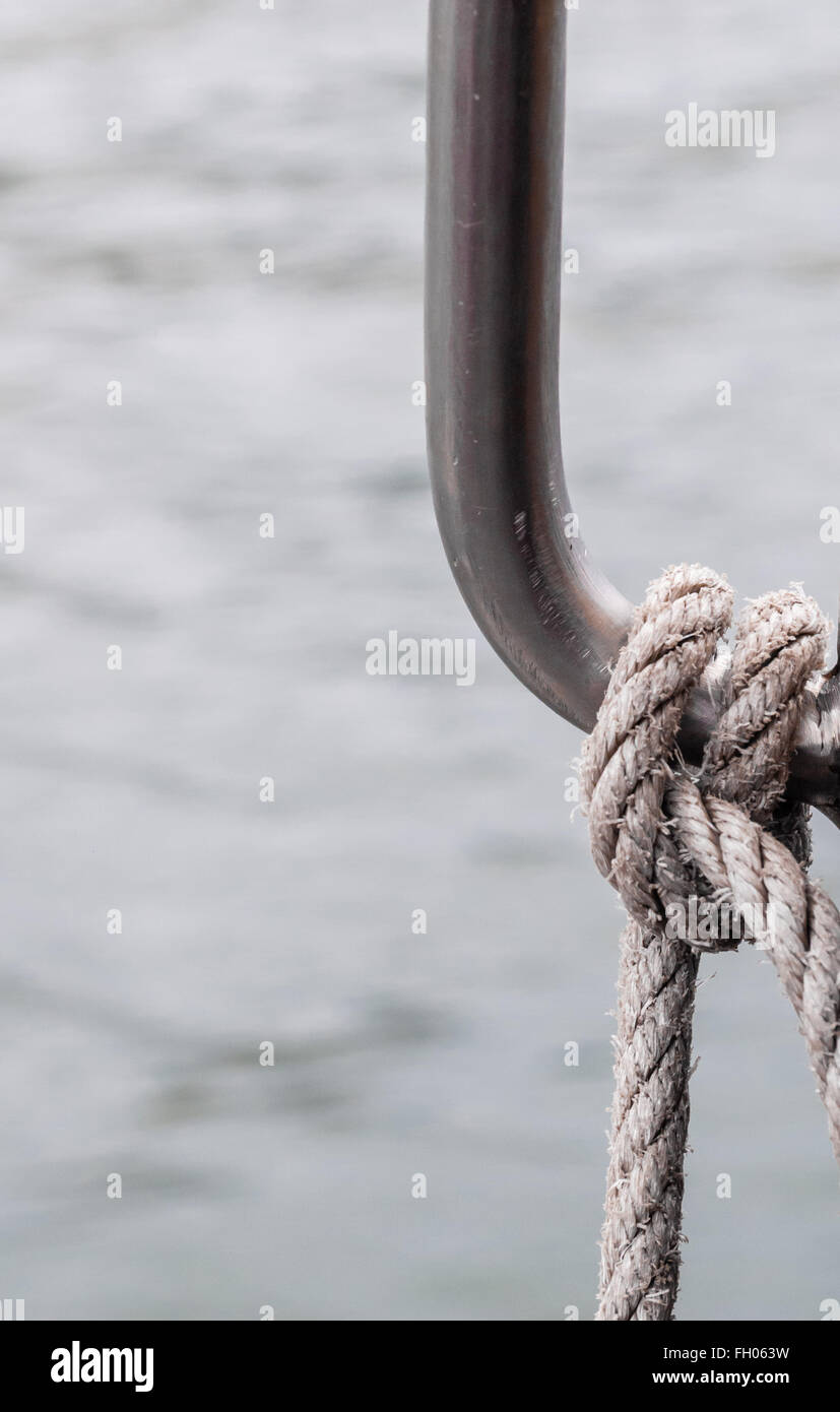 Verschlissenen Seil an Metallgriff gegen unscharfe Wasser gebunden. Stockfoto