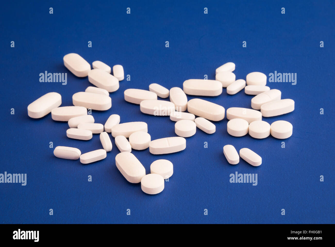 Verschiedene Größe und Form weißer Pillen auf blauem Hintergrund Stockfoto