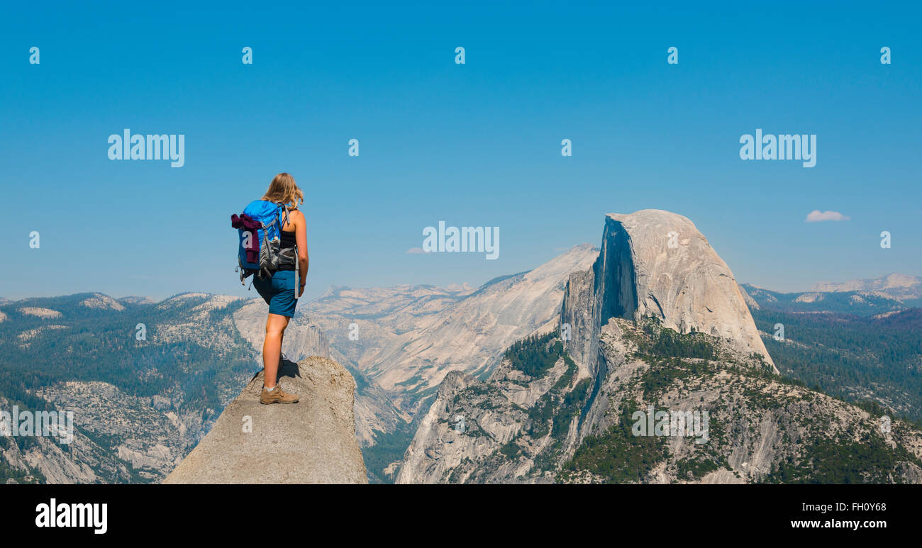 Wanderer auf einem Felsen stehend, mit Blick auf Half Dome, Blick vom Glacier Point, Yosemite-Nationalpark, Kalifornien, USA Stockfoto