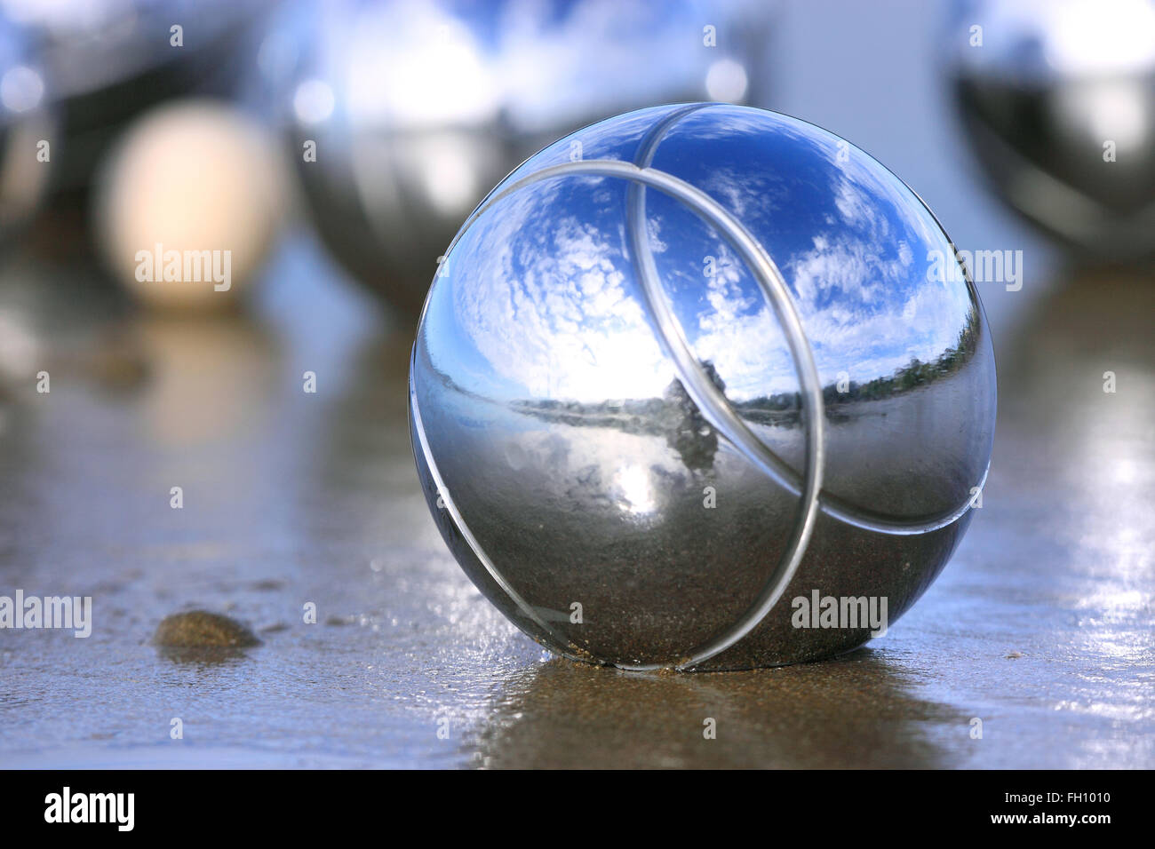 Eine Boccia-Kugel an einem Sandstrand mit anderen Boule im Hintergrund. Stockfoto