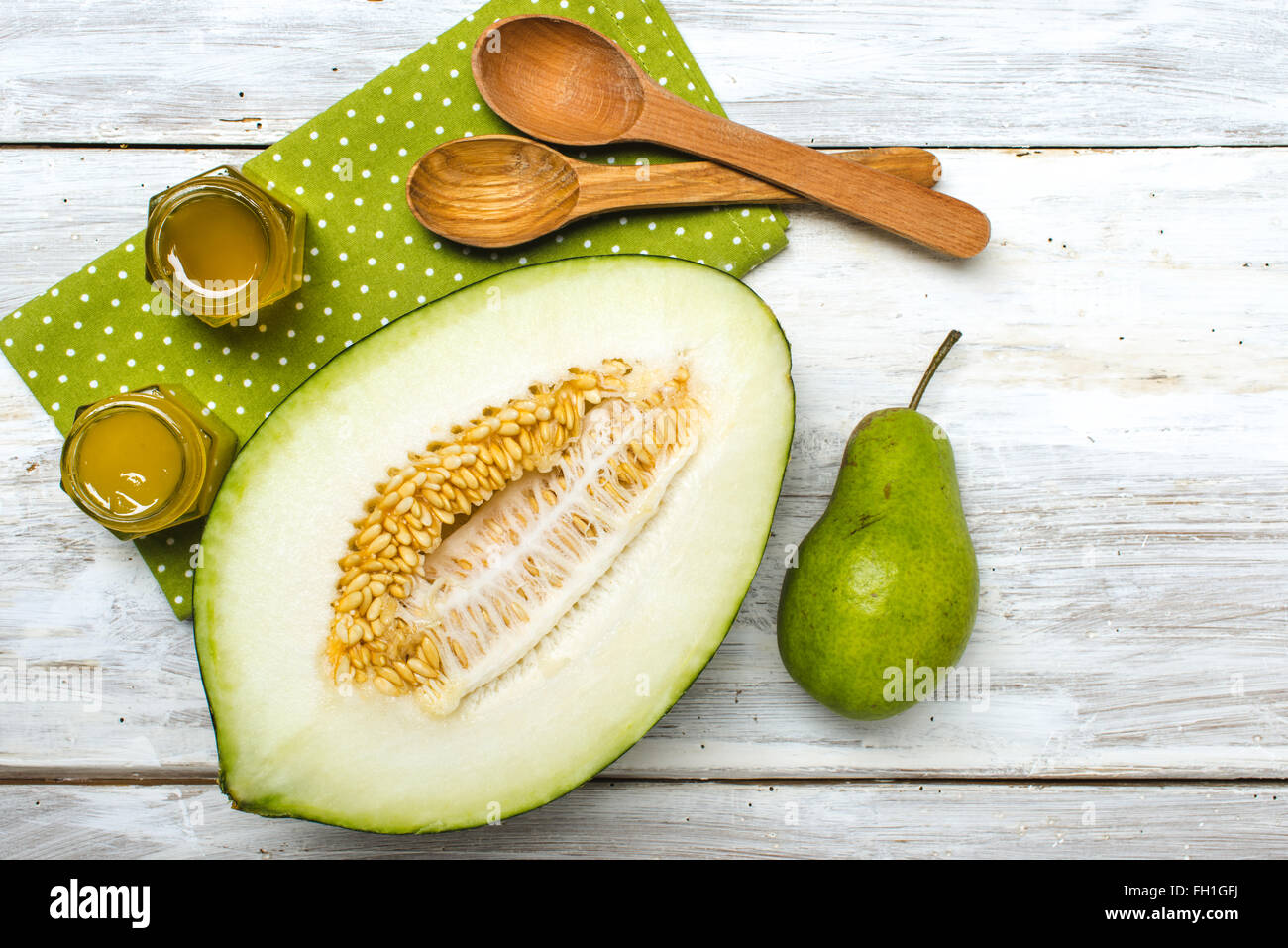 Gesunde grüne Melone, Birne und Honig auf rustikalem Holzbrett im rustikalen Stil Stockfoto