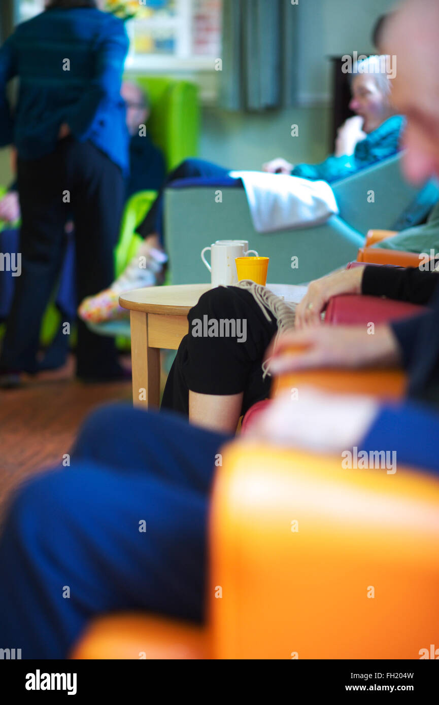 Ältere Männer und Frauen sitzen im Aufenthaltsraum eines Altenheims UK mit Tassen Tee auf Couchtisch Stockfoto