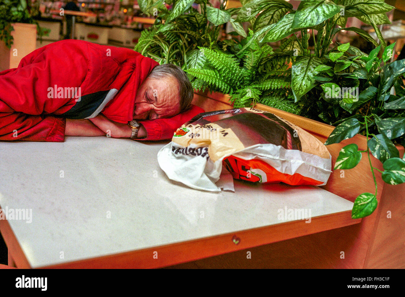 Müdigkeit schlafender alter Mann in einem Einkaufszentrum Einsamkeit Stockfoto