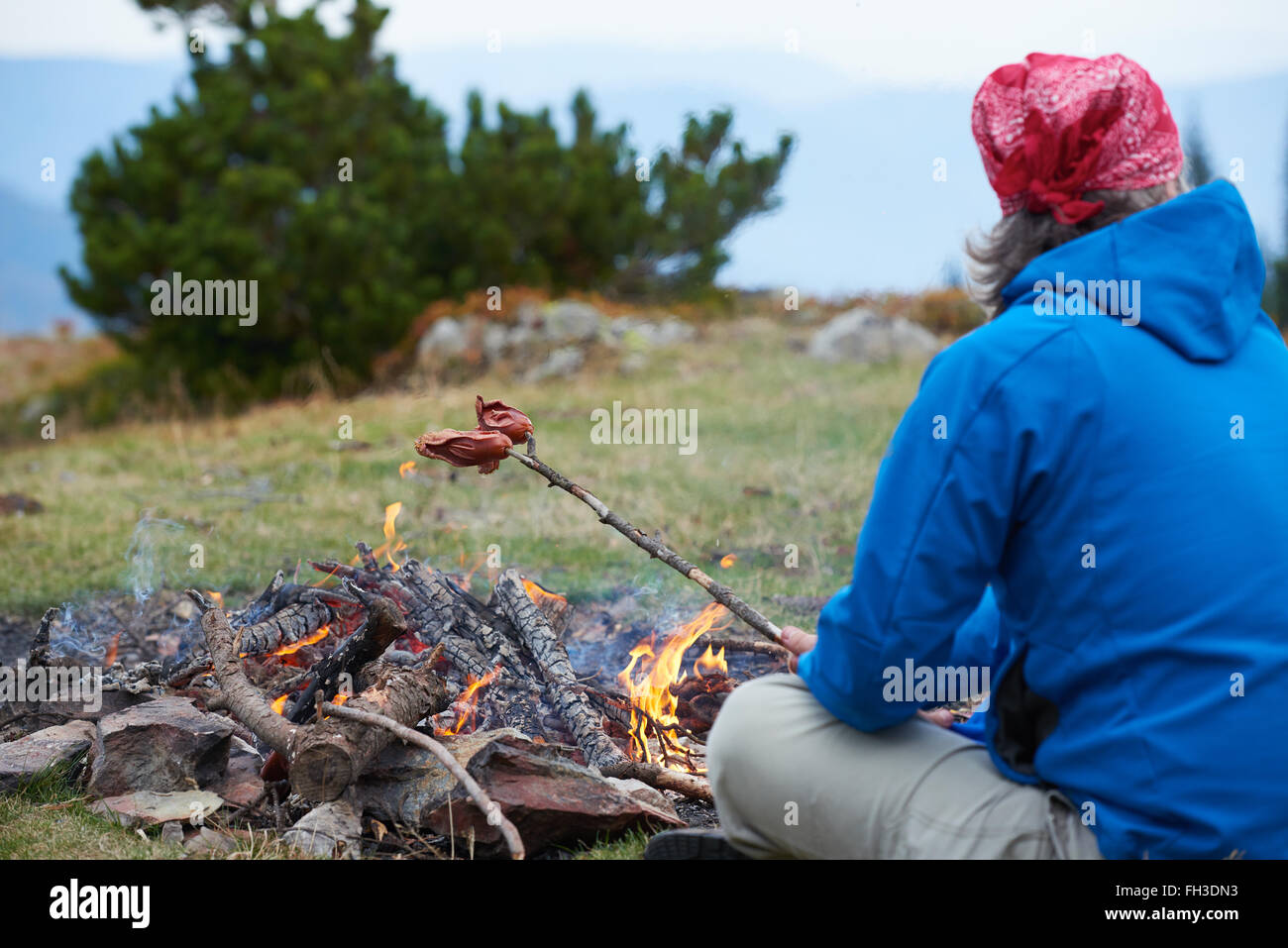 Wandern Menschen bereiten leckere Würstchen am Lagerfeuer Stockfoto