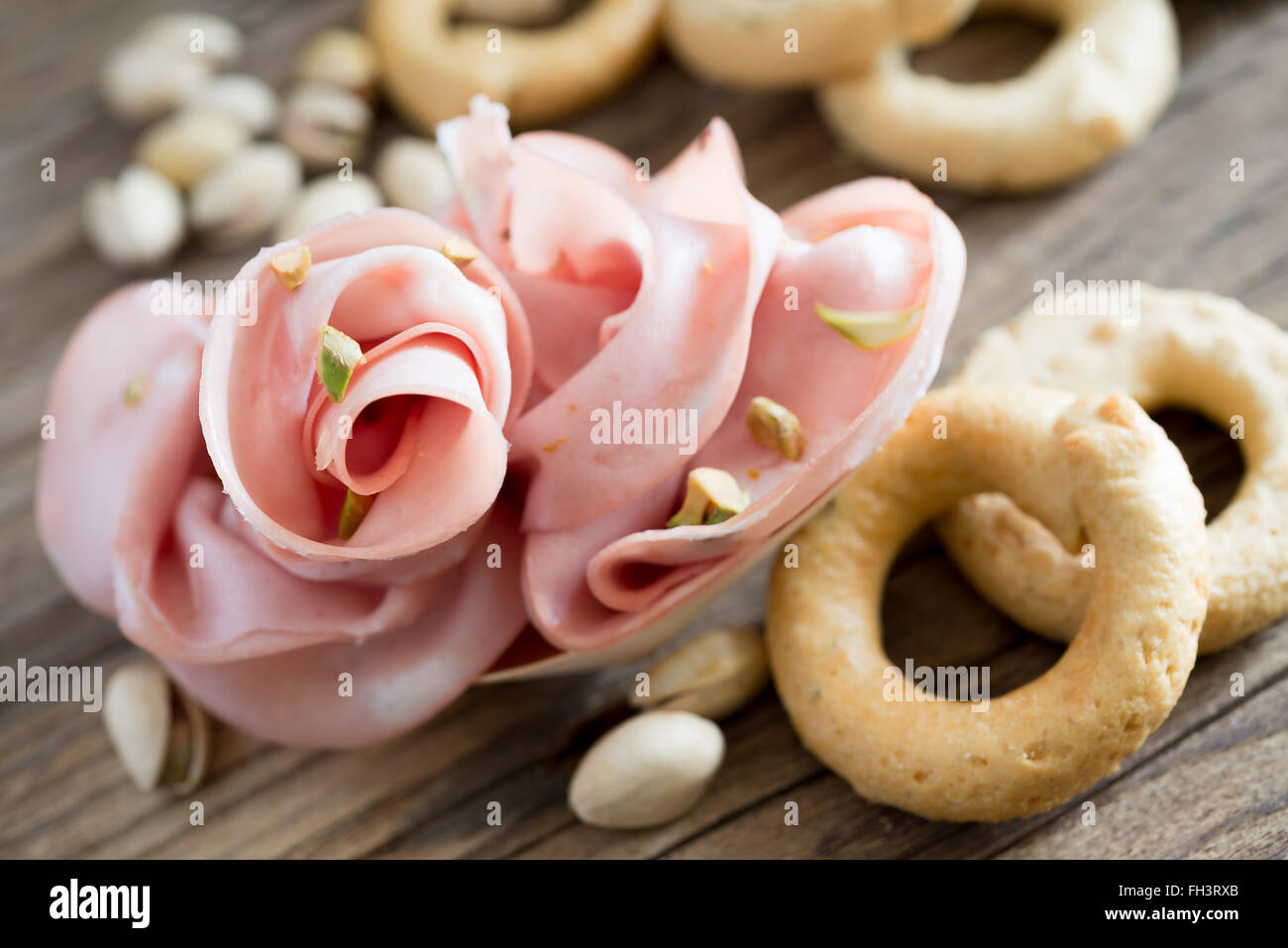 weiche Blumen Mortadella und Pistazien auf Holztisch Stockfoto