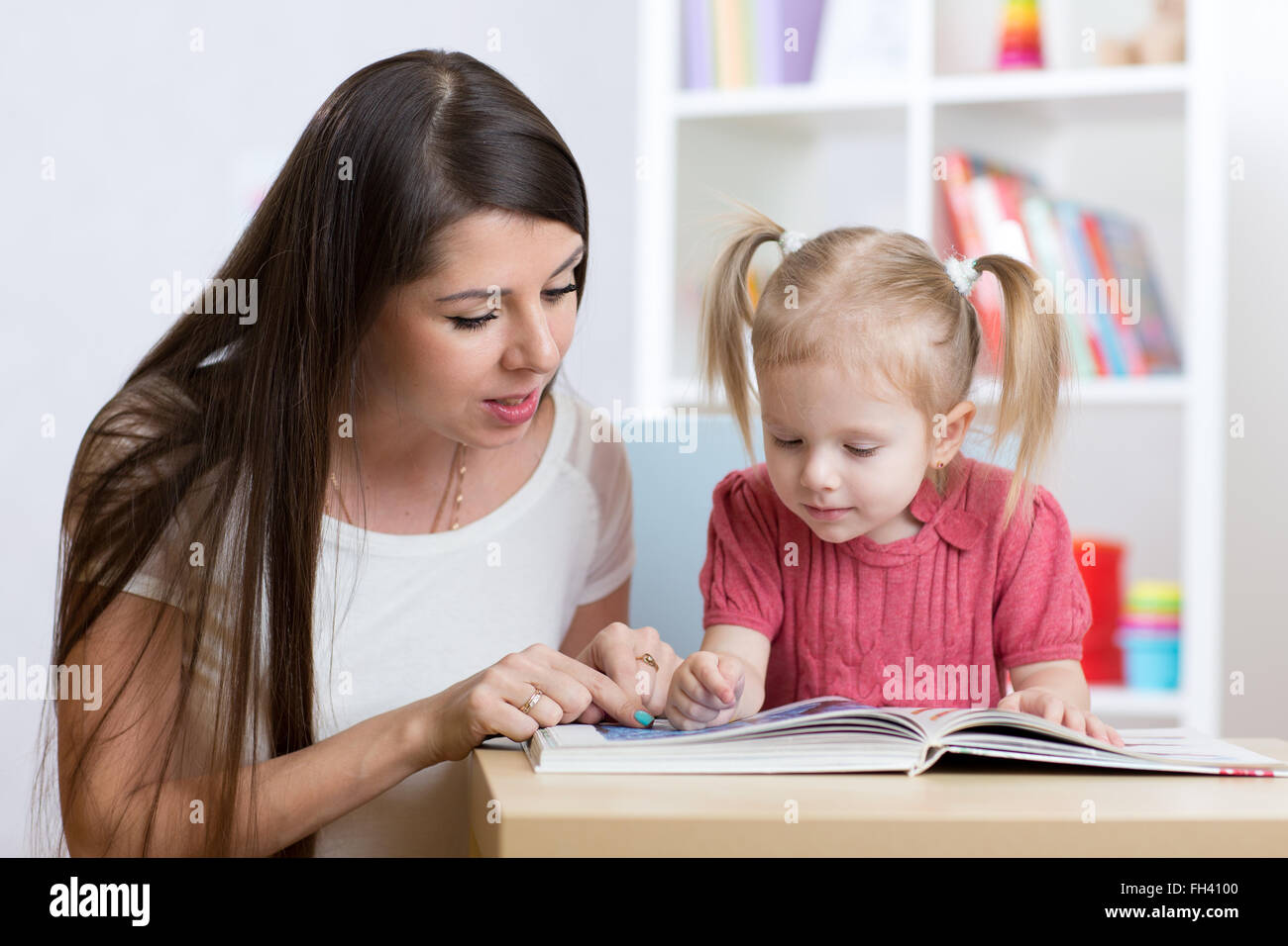 Junge Mutter liest Tochter Kind ein Buch. Stockfoto