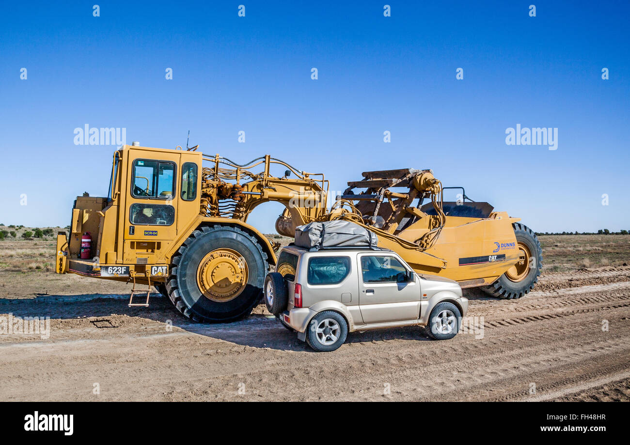 4WD Fahrzeug gegen eine riesige Caterpillar Motor Scraper Outback Straße Wartung Maschinen auf der neuen Strzelecki-Strecke in den Schatten gestellt Stockfoto