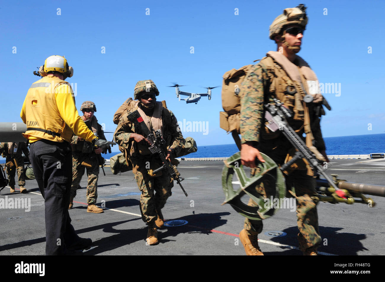 Pazifik (22. Februar 2016) Marines, der 13. Marine Expeditionary Unit zugeordnet (13. MEU), einen Hubschrauber auf dem Flugdeck der amphibischen Angriff Schiff USS Boxer (LHD4) aussteigen, während ein MV-22 Osprey vorbereitet zu landen. Mehr als 4.500 Matrosen und Marinesoldaten aus Boxer amphibische bereit Gruppe und der 13. Marine Expeditionary Unit (MEU 13.) führen Durchhaltefähigkeit Training vor der Küste von Hawaii in der Vorbereitung für die Eingabe der US 5. und 7. Flotte Arbeitsbereiche Stockfoto