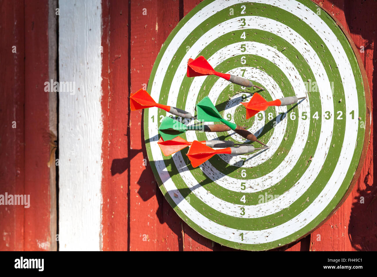 Dart-Ziel mit vielen Pfeilen hängen rote Holzwand Stockfoto