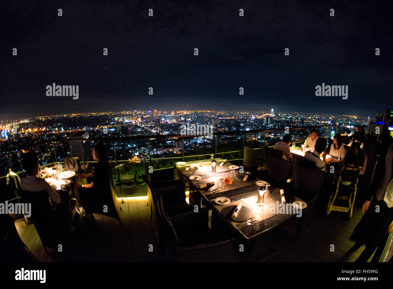Bangkok Skyline bei Nacht vom Vertigo Restaurant Thailand // BANGKOK, Thailand – die glitzernde Skyline von Bangkok erstreckt sich unterhalb des Hotels vom Vertigo Restaurant auf dem Dach des Banyan Tree Hotels aus. Wolkenkratzer und Hochhäuser beleuchten die weitläufige thailändische Hauptstadt mit unzähligen Lichtern und schaffen ein atemberaubendes Stadtpanorama. Stockfoto