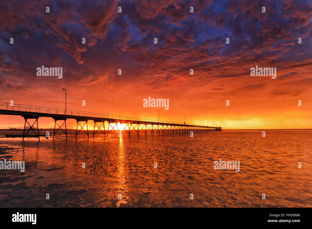 Holz in kleinen Küstenort Ceduna bei schweren Sturm bei orange Sonnenuntergang Steg. Bewölkter Himmel spiegelt sich in stürmischen Zeiten der Fischerei Stockfoto