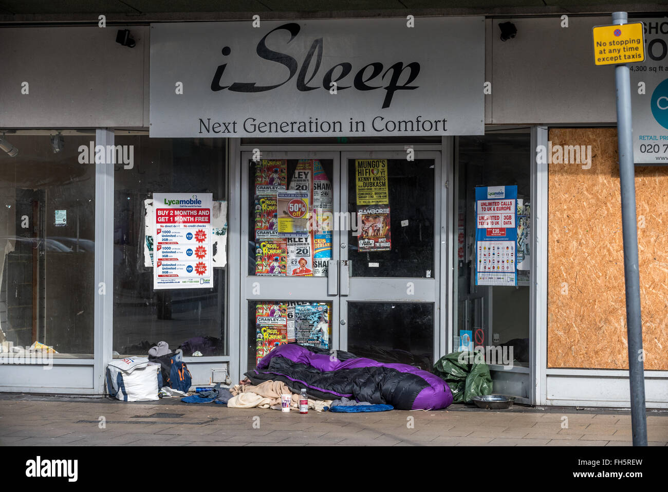 Ein Obdachloser schläft in der Tür eines stillgelegten Bettwaren-Shop in Crawley, West Sussex. Stockfoto