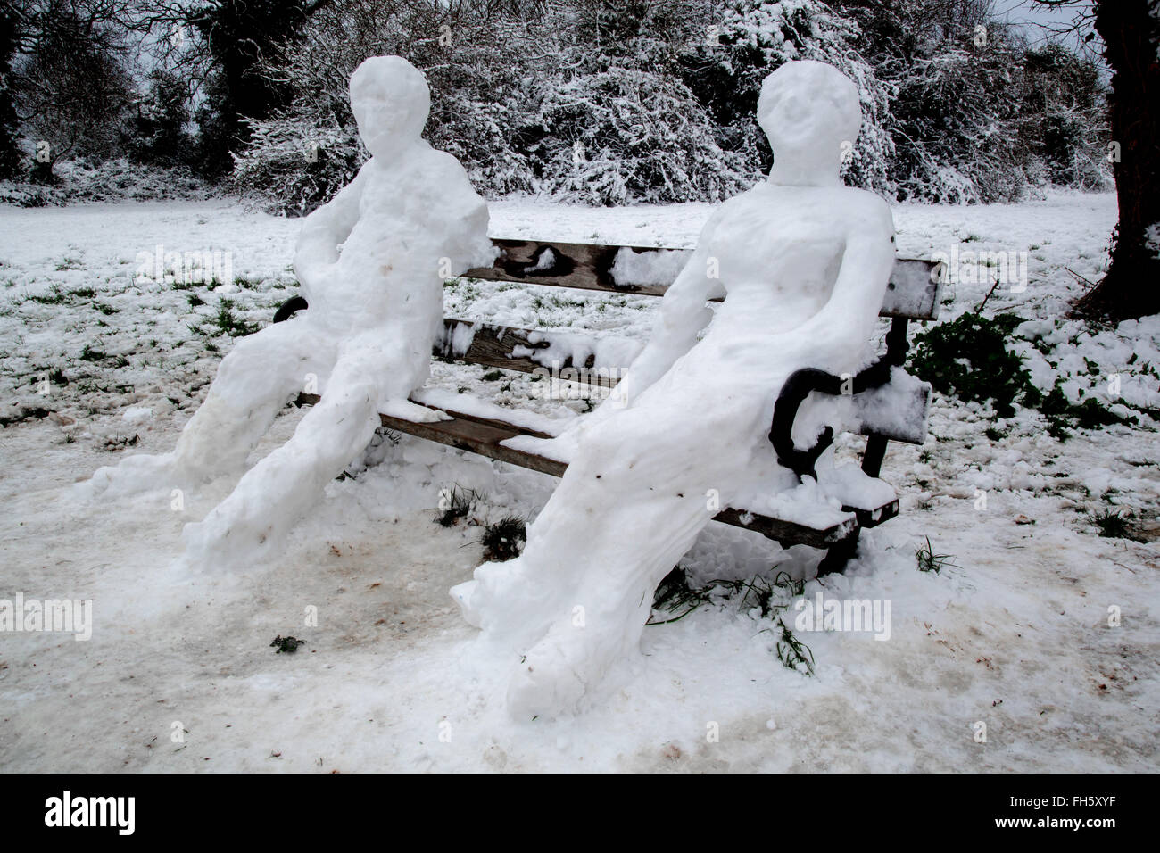 Mann und Frau Schnee Skulpturen sitzen auf einem gefrorenen Parkbank in Clifton Bristol UK Stockfoto