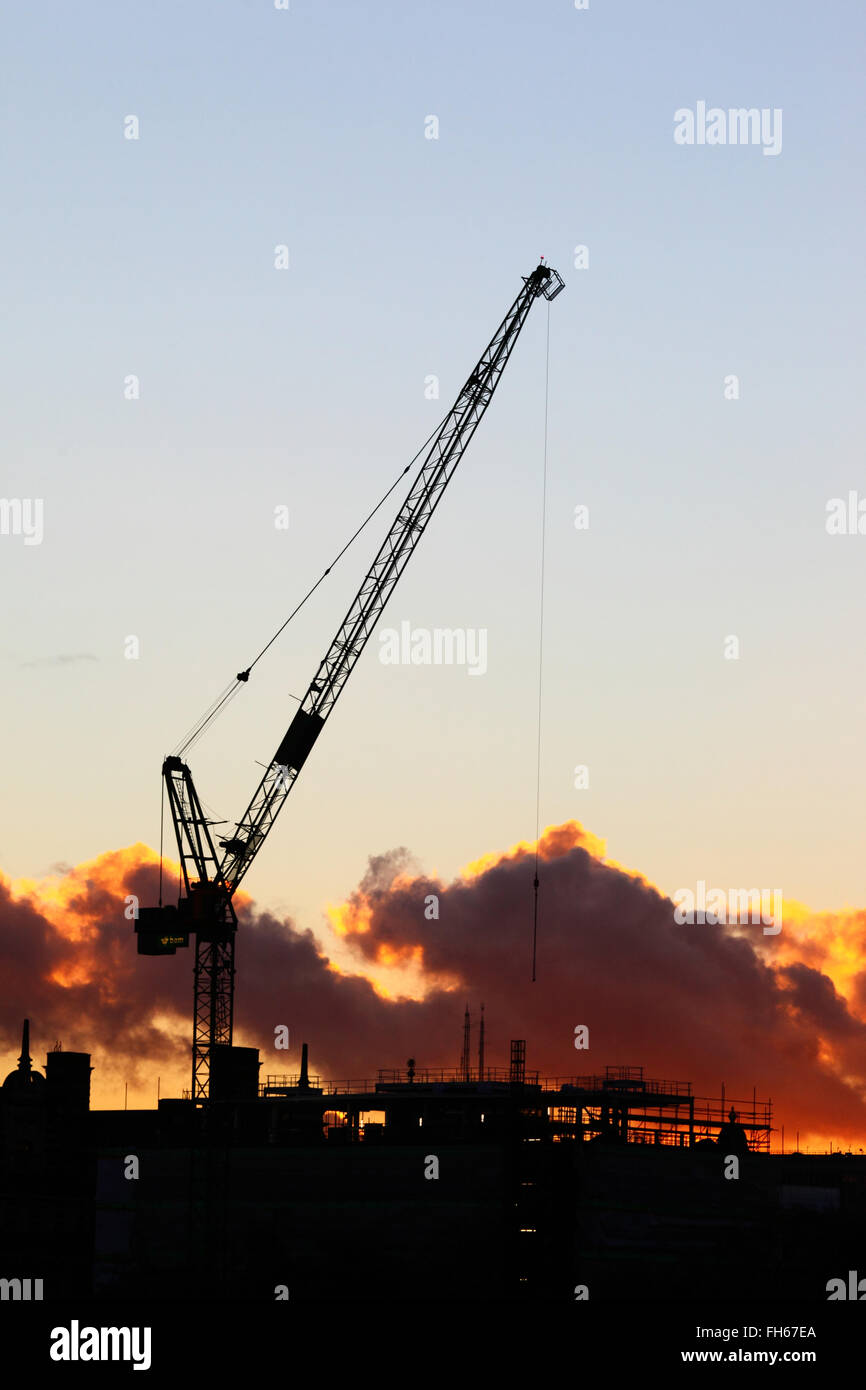 Turmkran mit Wippausleger auf der Baustelle, Silhouette am Himmel bei Sonnenuntergang, London, England, Großbritannien Stockfoto
