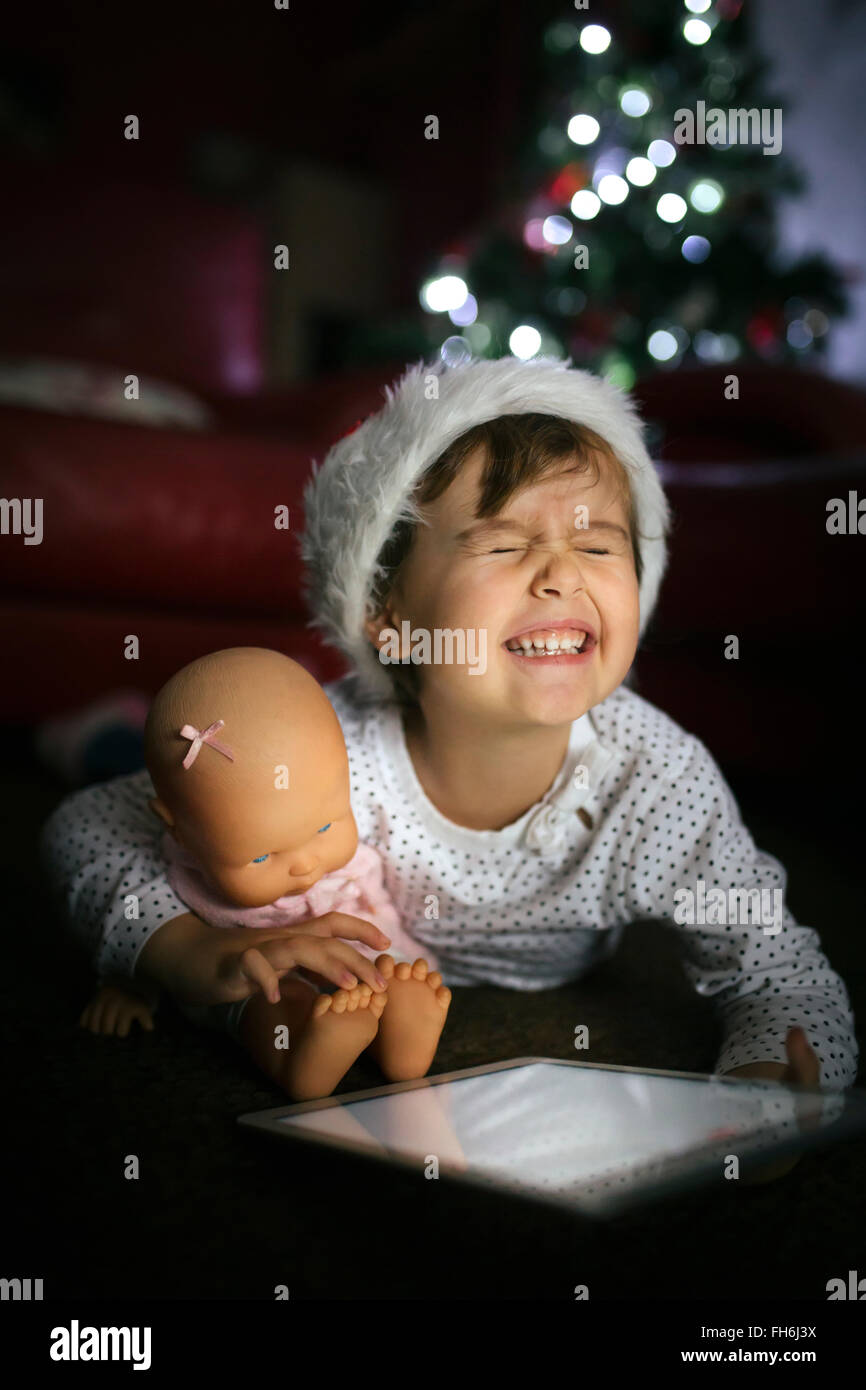 Porträt von kleinen Mädchen mit Weihnachten Mütze mit digital-Tablette und Puppe zu Hause Stockfoto