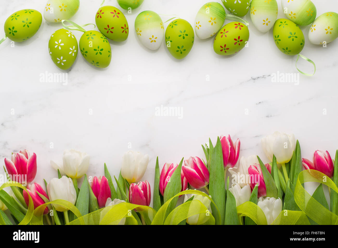 Ostereier und Tulpen auf weißem Marmor Stockfoto