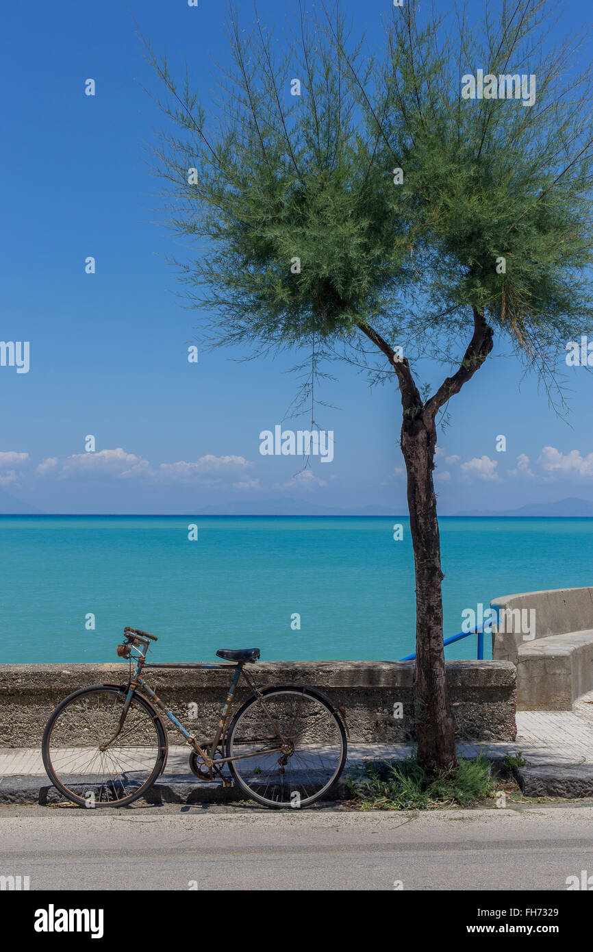 Altes Fahrrad durch Wand neben Baum vor Mittelmeer, Äolischen Inseln Salina, Lipari und Vulcano hinter Stockfoto